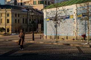 A woman walks next to the ‘Wall of Remembrance of the Fallen for Ukraine’ in Kyiv